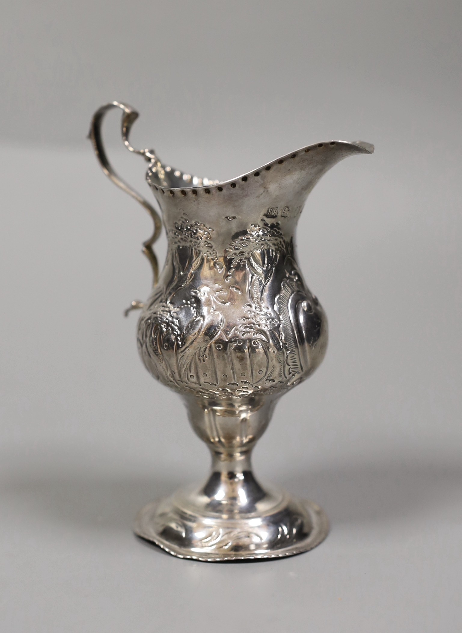 A George III silver inverted pear shaped cream jug, with later embossed decoration, Stephen Adams I, London, 1787, 12.3cm, 73 grams.